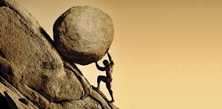 A man pushing a boulder up a rock face