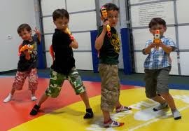 Four small boys pointing toy guns at the camera
